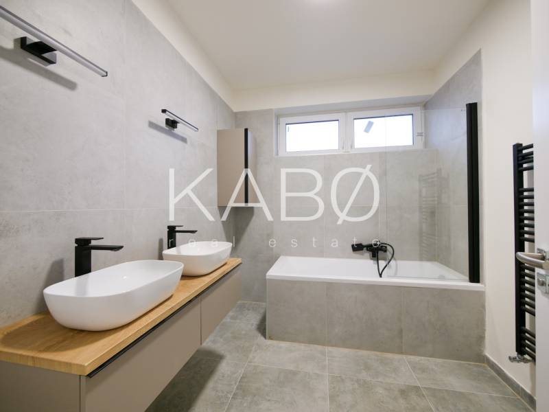 A bathroom in a family house with two sinks, a bathtub, and an elegant interior.