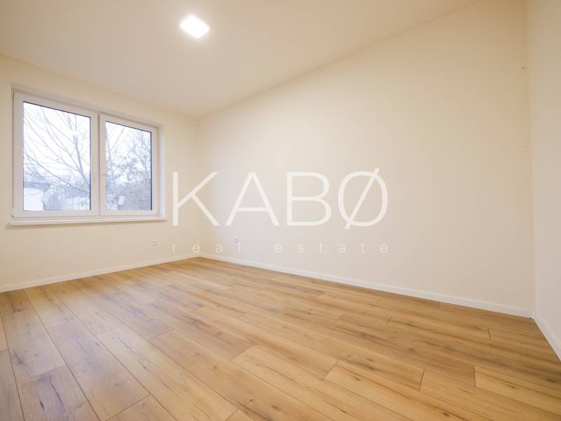 A room with a wooden floor decor and a large window in a family house.