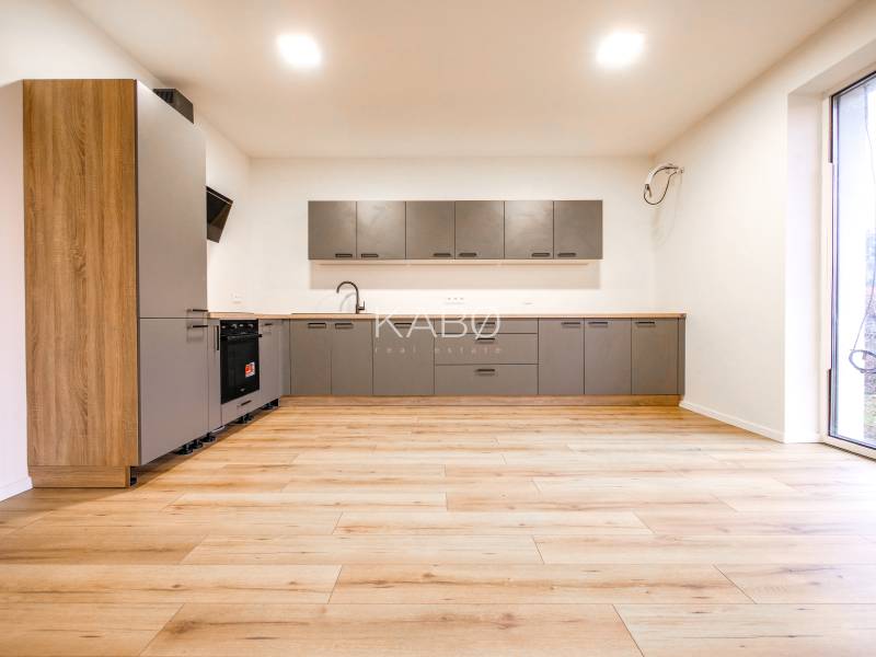 A kitchen in a family house with a wooden decor floor and large windows.