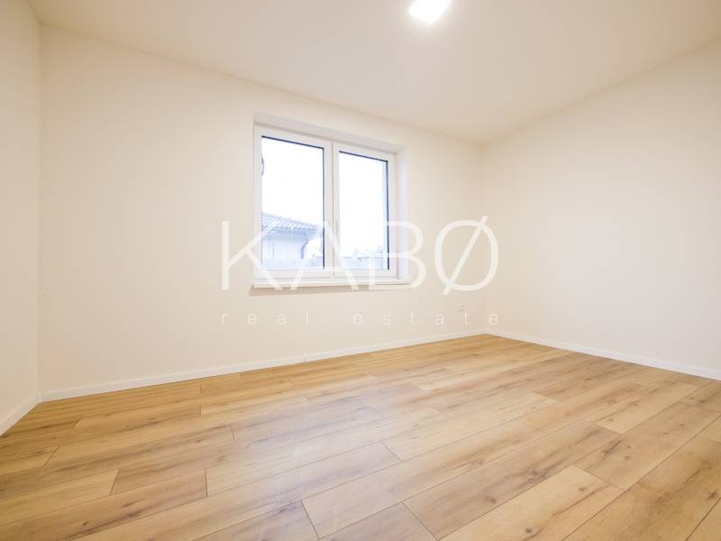 A room in a family house with a wooden decor floor and a large window.