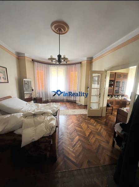 Bedroom in a family house with a bed, curtains, and a wooden decor floor.
