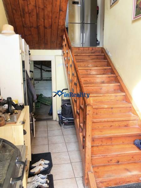 Interior of a family house with a wooden staircase and a refrigerator in the background.