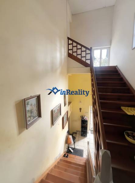 A staircase in a family house with a wooden railing and pictures on the walls.