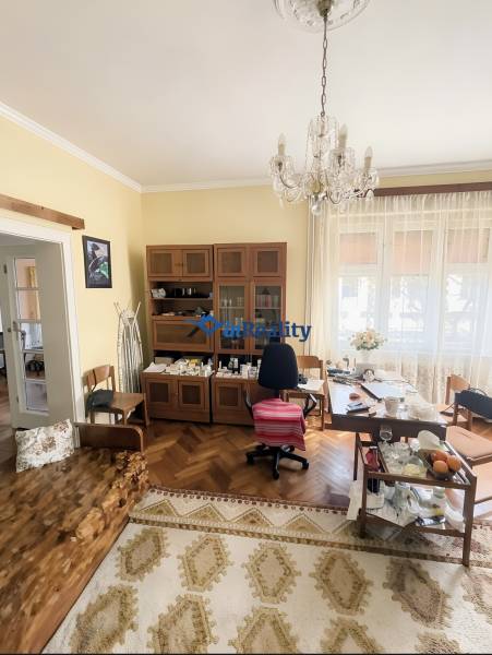 A room in a family house with a chandelier, wooden decor flooring, and furniture.