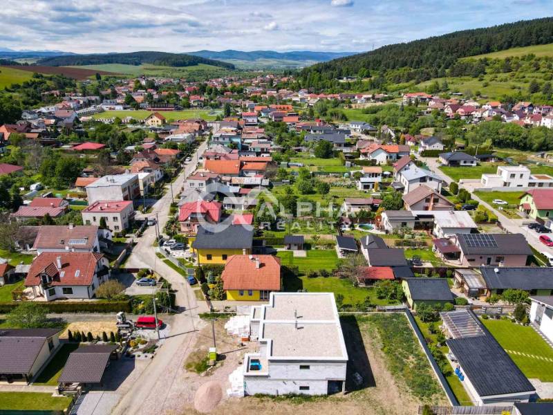 An aerial view of the residential development of family houses in Harichovce, surrounded by greenery and hills.