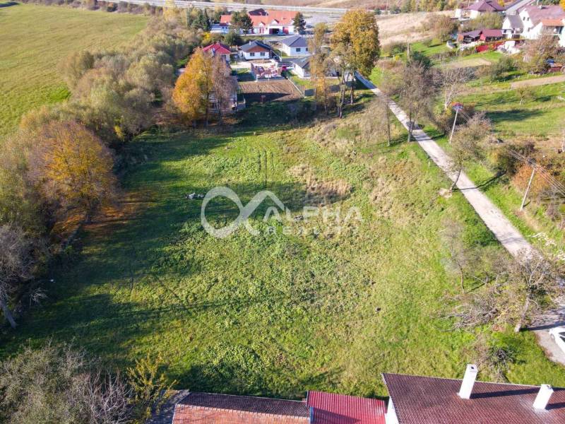 Residential plots in Spišské Podhradie surrounded by greenery and nearby houses.