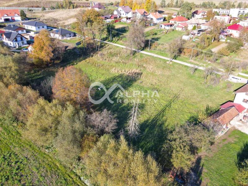 Residential plots in Spišské Podhradie surrounded by greenery and neighboring houses.