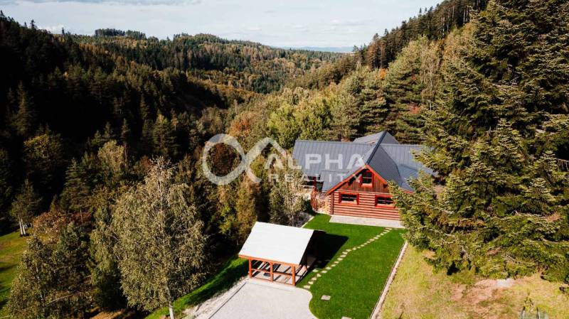 A family house in Hnilčík, surrounded by forests with a large grassy area and a gazebo.