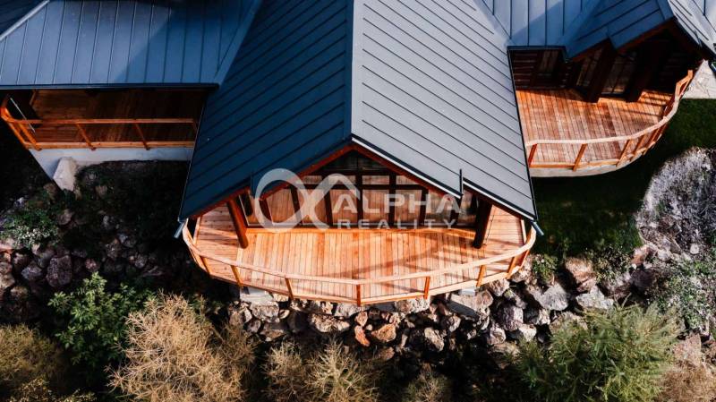 A family house in Hnilčík with a wooden terrace and a sloped roof among natural elements.