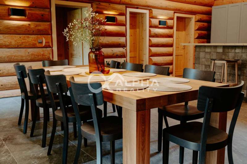 A dining room with a table and chairs, wooden walls, a floor with a wooden decor in a family house.