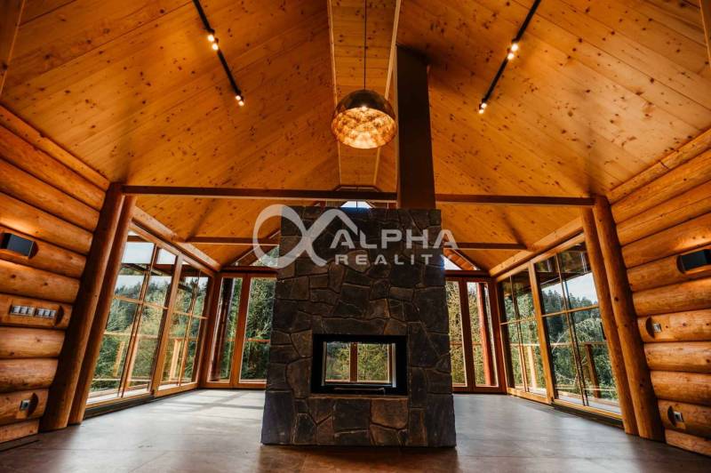Wooden interior of a family house with a fireplace and large windows, floor with wooden decor.