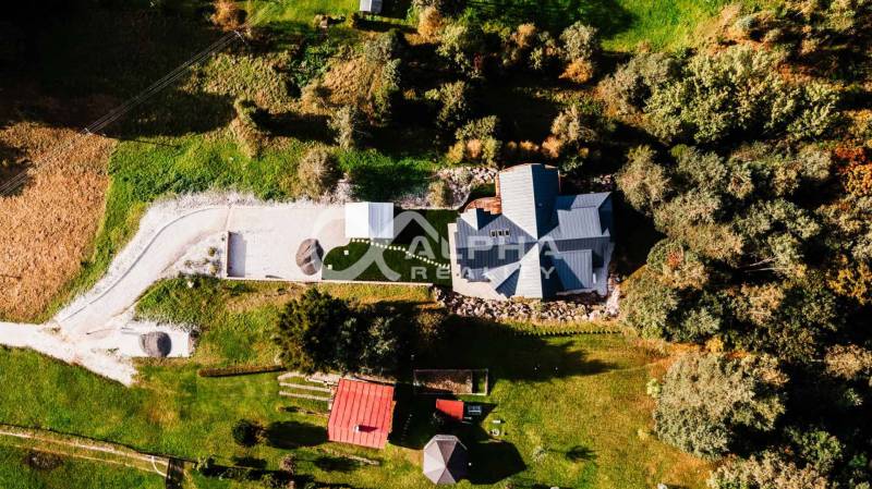 Aerial view of a family house in Hnilčík surrounded by greenery and an access road.