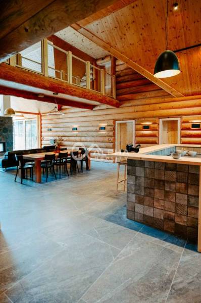 Interior of a family house with wooden walls, a dining table, and a light floor with a wooden decor.