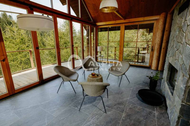 A stone fireplace in a family house with a glass wall and natural scenery.