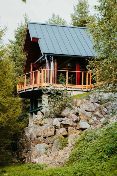 A wooden family house in Hnilčík surrounded by rocks and nature.