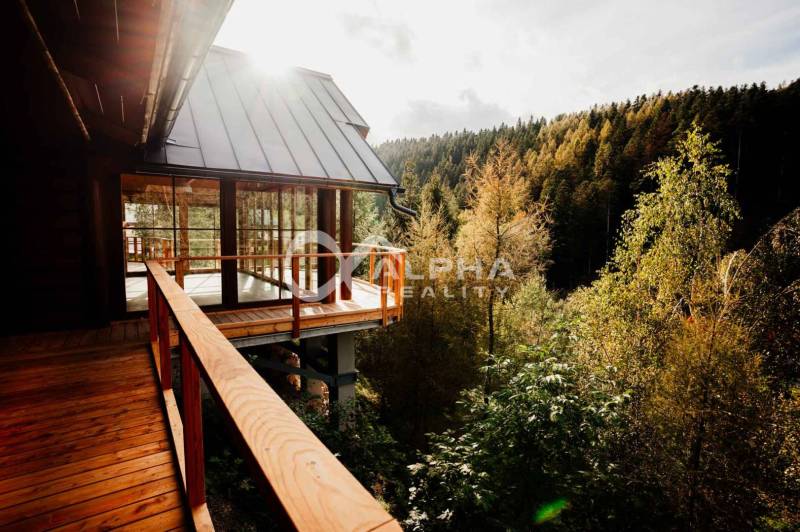 The family house in Hnilčík is surrounded by forest and has a wooden terrace with a view.