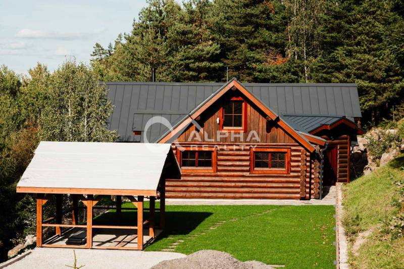 A wooden family house in Hnilčík surrounded by a lawn and trees in a natural setting.