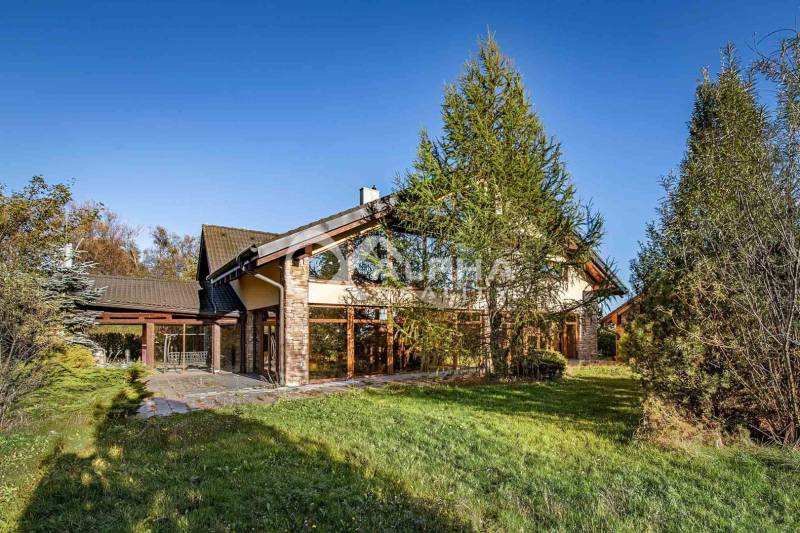 A family house in Veľká Lomnica is surrounded by greenery, with a stone facade and trees in the vicinity.