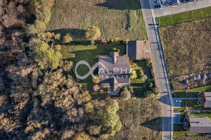 A family house in Veľká Lomnica surrounded by greenery and neighboring plots from a bird's eye view.