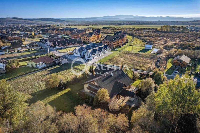 Aerial view of family houses in Veľká Lomnica with surrounding countryside and mountain backdrop.