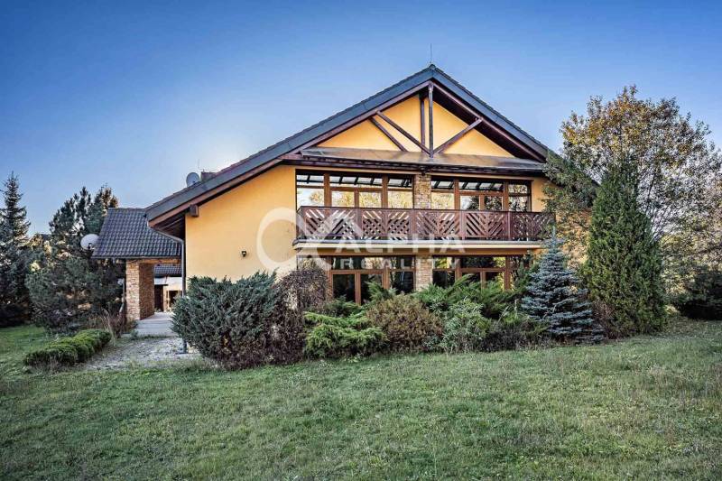 A family house in Veľká Lomnica with wooden elements, surrounded by greenery and a lawn.