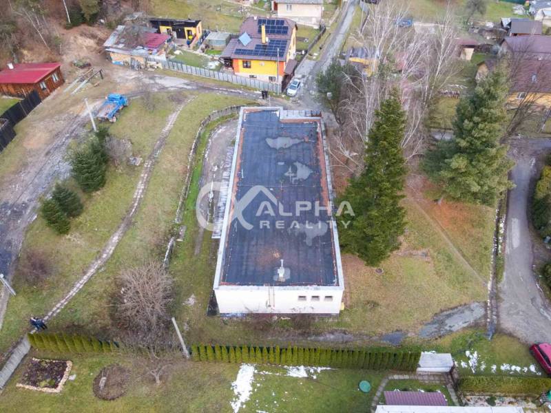 Aerial view of a building in Helcmanovce, surrounded by greenery and nearby houses.