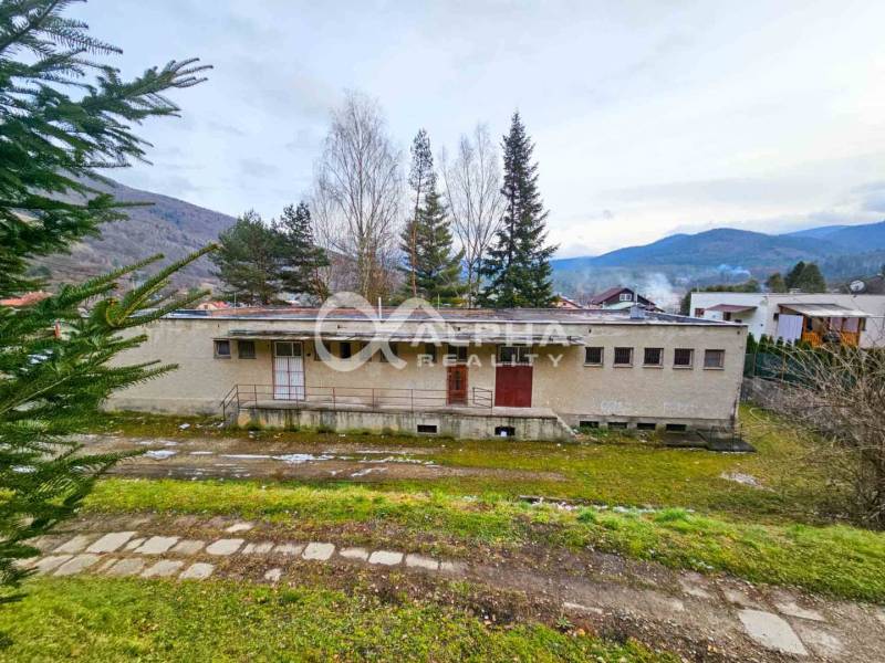 A building in Helcmanovce surrounded by nature with hills in the background.