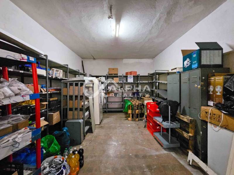 Room with shelves, metal cabinets, and various items on a wooden-decorated floor.