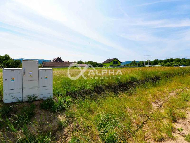 Plots - housing in Betlanovce with greenery, houses, and electrical cabinets in the background.