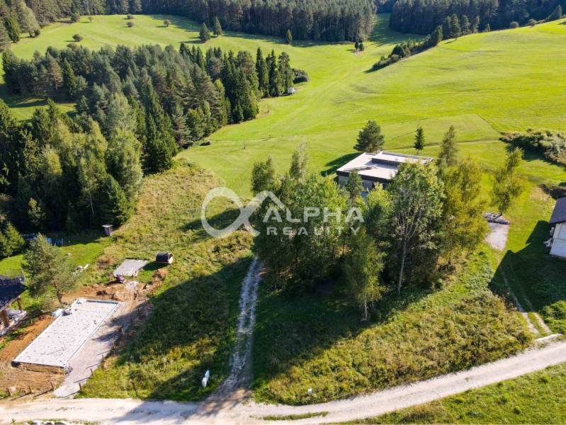 The hilly landscape in Spišské Vlachy, surrounded by greenery and houses, is suitable for residential plots.
