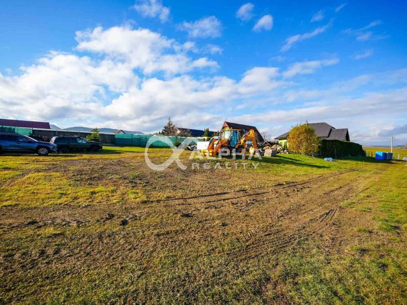 Residential plots in Spišské Tomášovce with cars and construction machinery.
