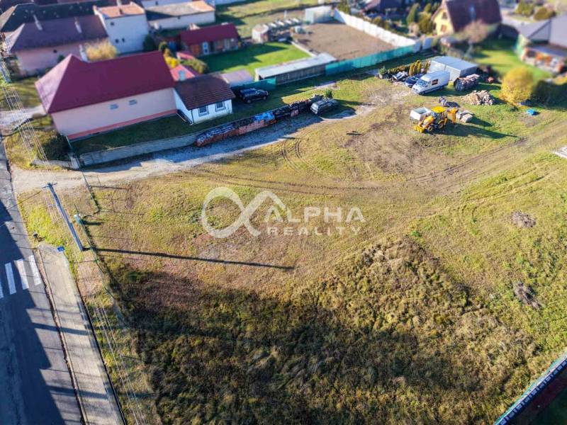 Lands in Spišské Tomášovce for housing, surrounding houses, construction equipment, grassy area.
