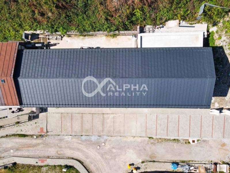 A view from above of a long building with a roof, parking, and surrounding greenery in Spišská Nová Ves.