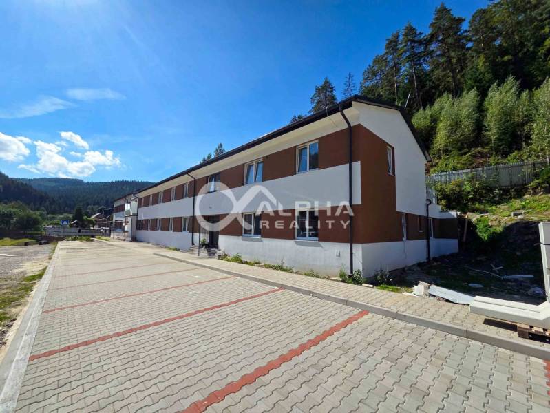 An apartment building in Spišská Nová Ves surrounded by greenery and a paved road.