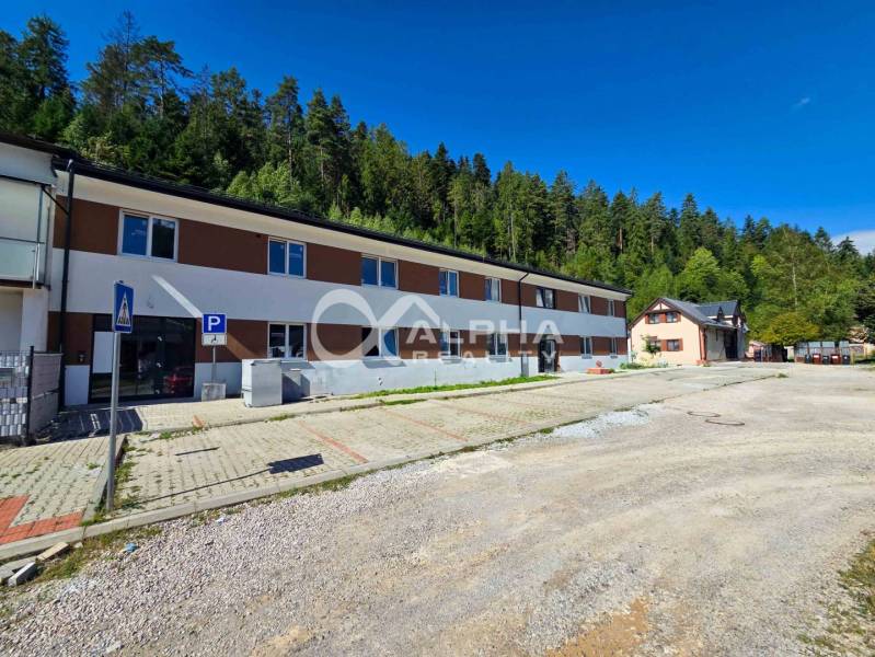 The exterior of a 3-room apartment in Spišská Nová Ves surrounded by a forest and a parking lot.
