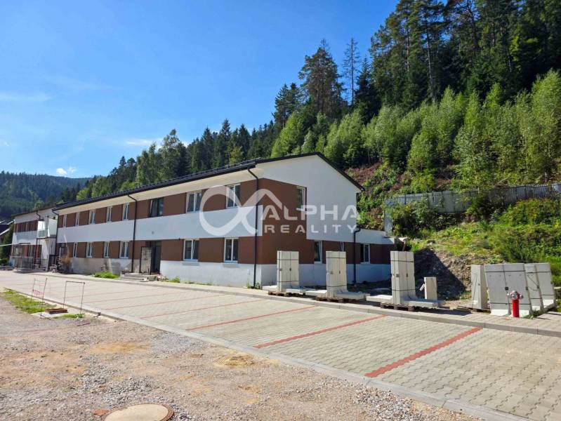 An apartment complex in Spišská Nová Ves surrounded by greenery, with paved parking areas in front of the building.