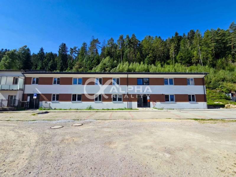 A building in Spišská Nová Ves near the forest, part of a 3-room apartment, parking lot in the foreground.