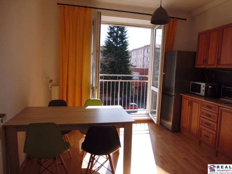 A kitchen in a studio apartment with furniture, yellow curtains, and a wooden decor floor.