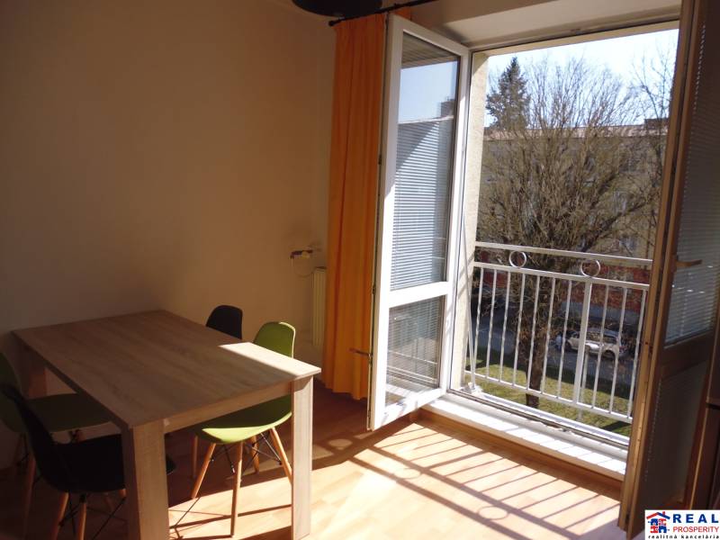 Open balcony in a one-room apartment with a wooden table and chairs.
