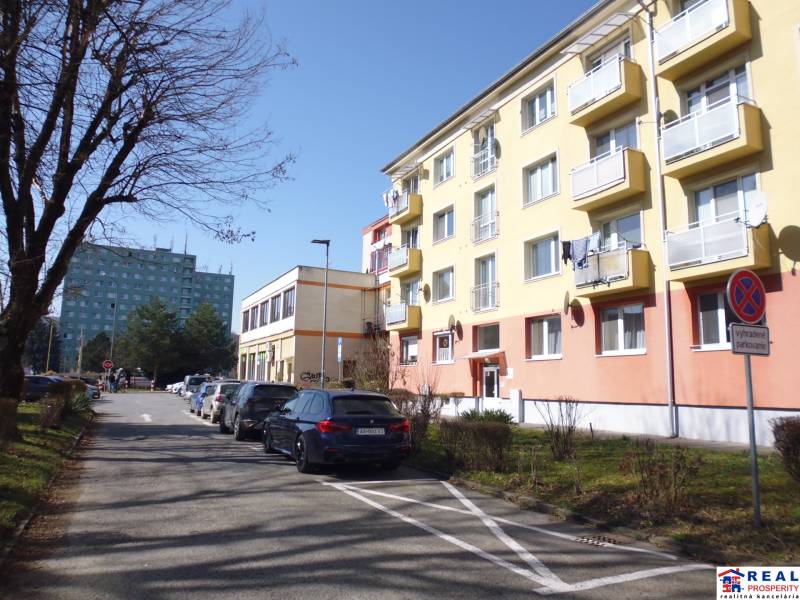 17th November Street in Prešov with apartment buildings and parked cars, suitable for a 1-room apartment.