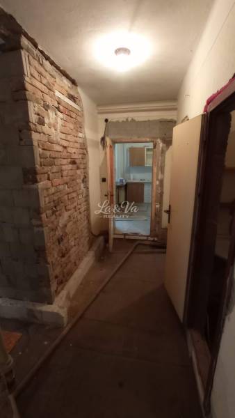 Hallway in a family house with exposed bricks and a passage to another room.