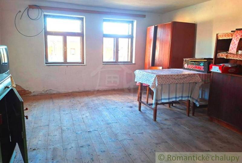 A room in a family house with a wooden decor floor, a wardrobe, and a table.