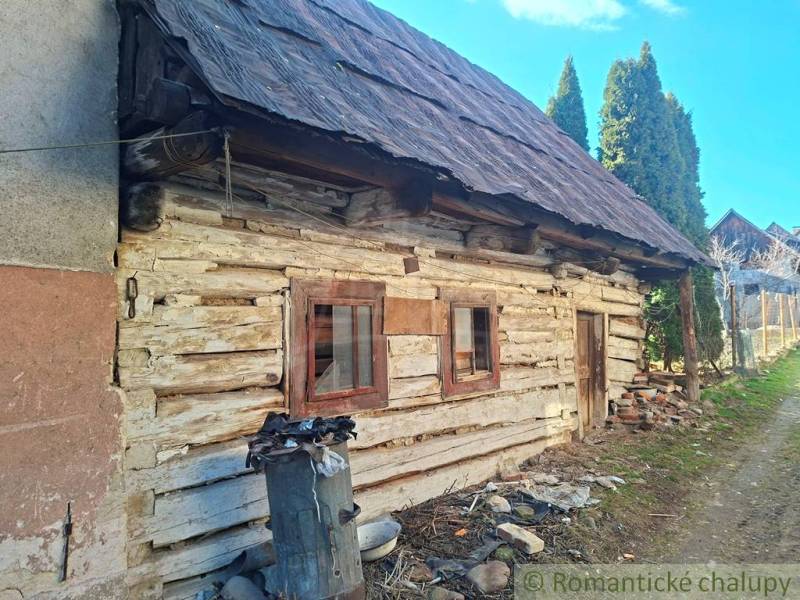 A wooden family house in Východná with a shabby facade and a metal barrel.