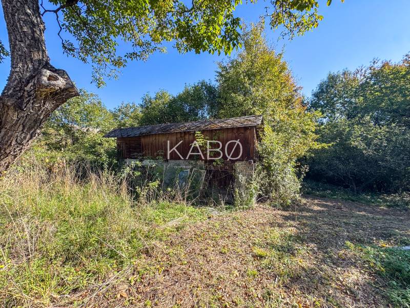 A wooden structure on agricultural and forest land in Lackov surrounded by greenery.