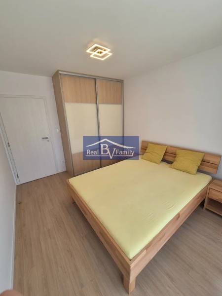 Bedroom with a double bed, built-in wardrobe, and wooden decor flooring in a 2-room apartment.