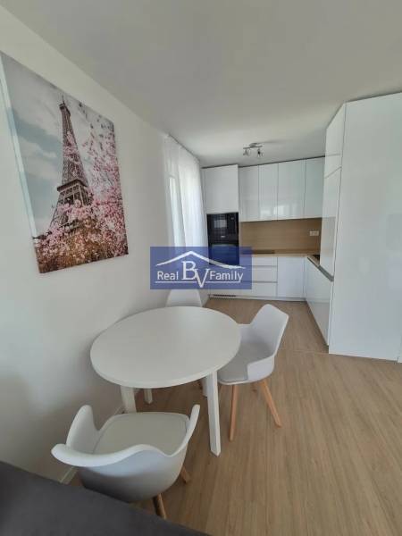 A kitchen in a 2-room apartment with a wooden decor floor and a dining table.