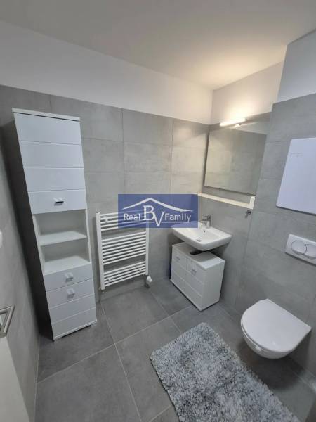 Bathroom in a 2-room apartment with white furniture and gray tiles.