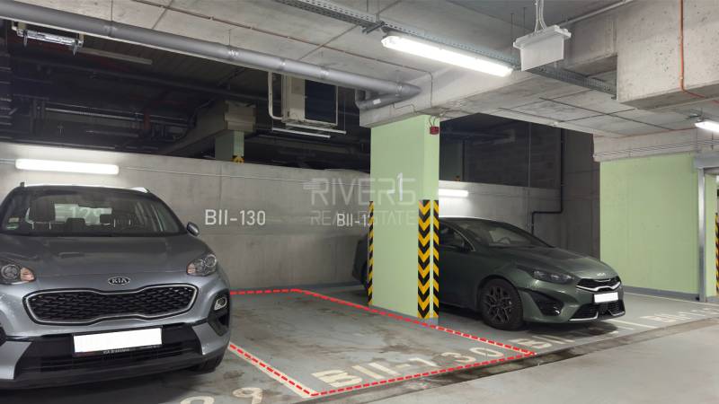 Parking space in garages with two cars, illuminated by fluorescent lights and marked BII-130.