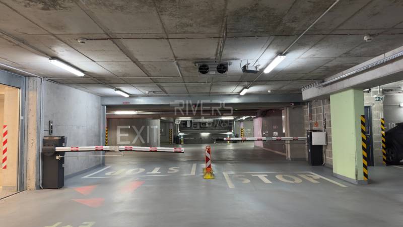 Parking lot in a garage with concrete walls, ramps, and signs Exit and Stop.