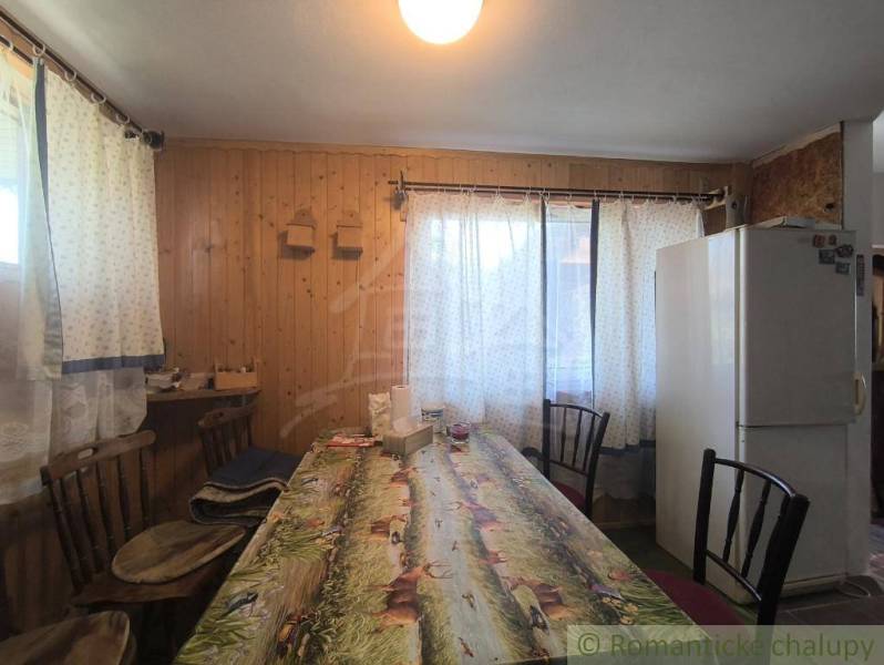 Dining room with a large table, refrigerator, and curtains, floor with wood decor.